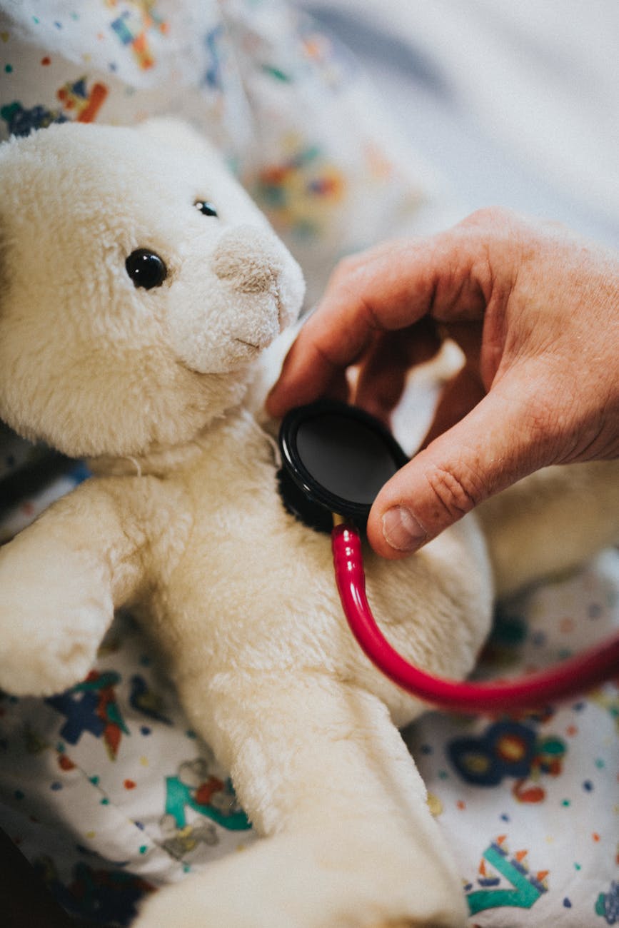 person using stethoscope on bear plush toy